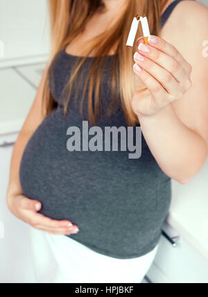 pregnant woman trying to qiut smoking and breaking cigarettes Stock Photo