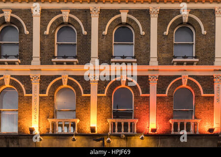 The pattern created by windows in a facade of a old victorian building in central london with bright colored lights in the botom Stock Photo