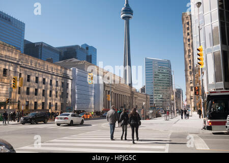 People going through a crosswalk at Front and Bay St. by Union Station with the CN Tower in the background. Stock Photo
