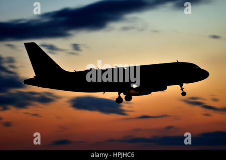 Silhouette of Airbus A319 passenger jet airplane landing in dusk, side view facing right Stock Photo