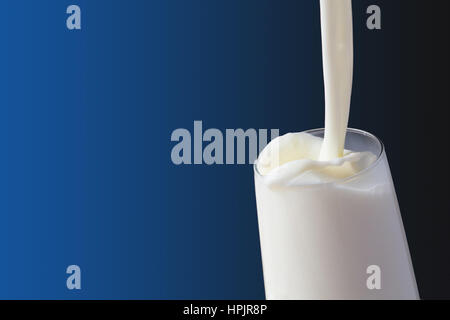 Milk splash in the glass on blue background Stock Photo