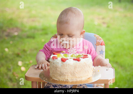 Child celebrating one year birthday with celebration fruit cake. Stock Photo