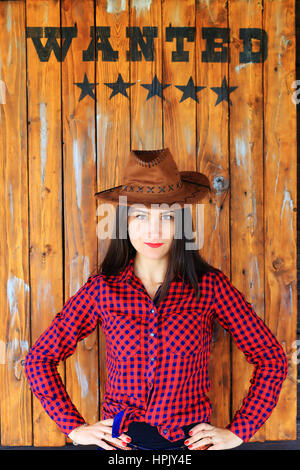 Wanted word over girl dressed in cowboy style on wooden background Stock Photo