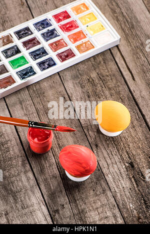 high angle view of colored eggs, paintbrush and paints for Easter