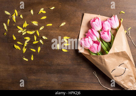 Top view of beautiful pink tulips bouquet wrapped in paper and yellow petals Stock Photo