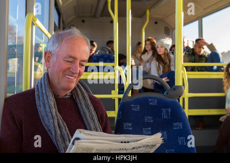 Happy senior man reading a newspaper on the bus. Stock Photo