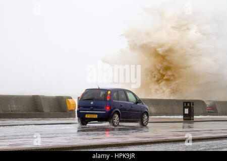 Storm Doris, New Brighton, Cheshire, UK. 23rd Feb 2017. Storm force winds and high stide batter  the Wirral Peninsula as she made land this morning.  Drivers had to be extra careful as winds gusting up to 80mph swept the 26' tidal surge onto the promenade as people made their way to work. Stock Photo