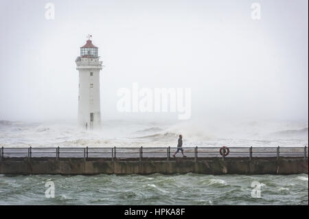 New Brighton, Wirral, UK. 23rd Feb, 2017. A man walks along the promenade, past the lighthouse, as Storm Doris hits the Wirral peninsula coastline, with strong winds and heavy rain. Credit: Paul Warburton/Alamy Live News Stock Photo