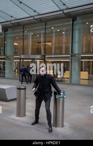 London, UK. 23rd February 2017. As Storm Doris blows across the UK, pedestrians on Fenchurch Street, brave the high winds funneled through the narrow streets, squeezed between the tall buildings of financial and insurance institutions in the City of London, on 23rd February 2017. Strong winds have led to flight cancellations and road and rail disruption across much of Britain. Thousands of homes have been left without power in Northern Ireland, Wales, Scotland and northern England. Richard Baker/Alamy Live News Stock Photo