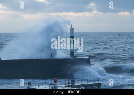 A man risking standing on a jetty as the big waves crash over him during storm Doris Stock Photo