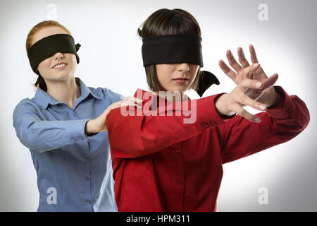 two business woman blind folded leading the other Stock Photo