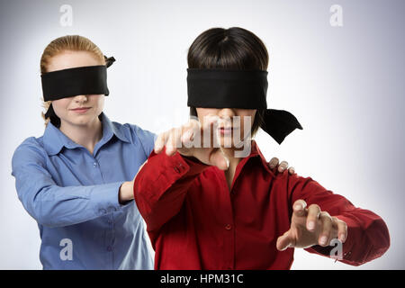 two business woman blind folded leading the other Stock Photo