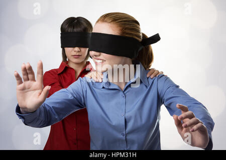 two business woman blind folded leading the other Stock Photo