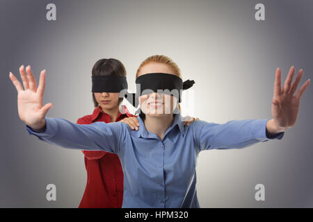 two business woman blind folded leading the other Stock Photo
