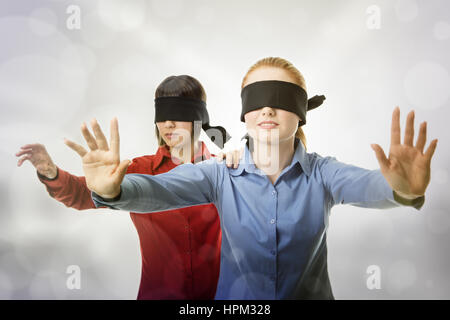 two business woman blind folded leading the other Stock Photo