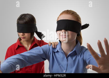 two business woman blind folded leading the other Stock Photo