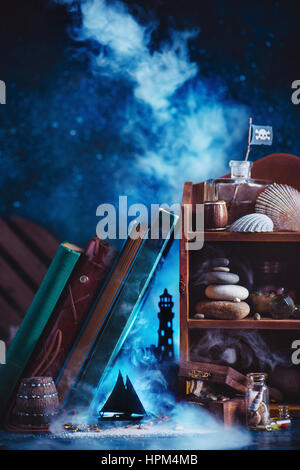 Marine still life with books, Jolly Roger sea shells, stones and paper silhouettes of a lighthouse and a sailing ship Stock Photo