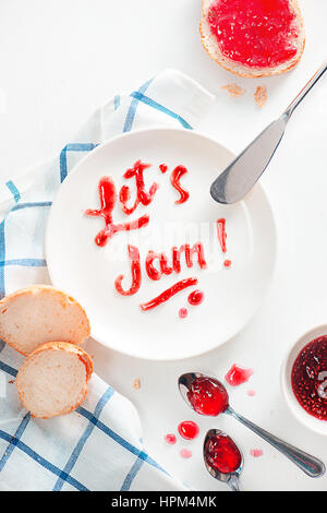 Raspberry jam lettering on a white wooden background with baguette Stock Photo