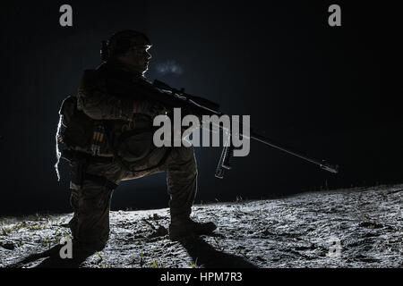 Army sniper with big rifle sitting holding rifle Stock Photo