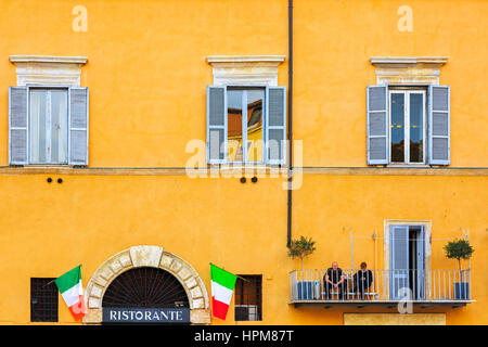 Couple sitting on the balcony of their apartment in Rome city centre, Rome, Italy Stock Photo