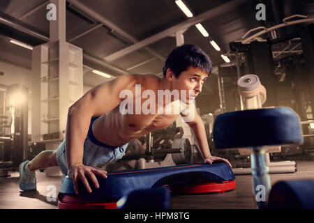 Athletic man is pushed to the floor in the gym Stock Photo