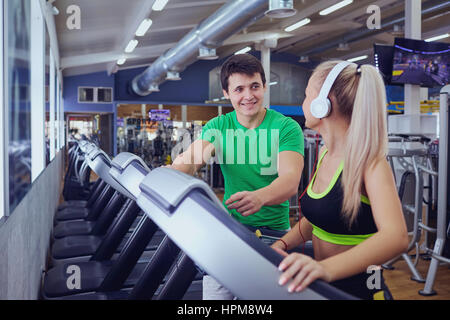 Personal trainer man with athletic girl on a treadmill in the gy Stock Photo