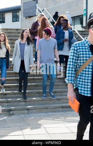 A group of young teenage students smile as they walk through the city on a break from university. They are carrying their books and digital tablets. Stock Photo