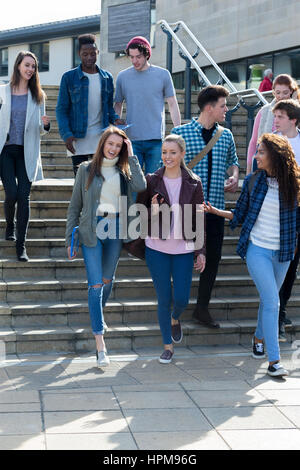 A group of young teenage students smile as they walk through the city on a break from university. They are carrying their books and digital tablets. Stock Photo