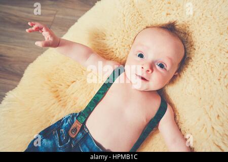 Little boy at home. Adorable baby resting on the fur blanket. Stock Photo