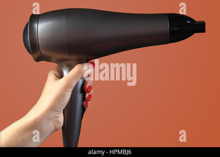 Hairdryer in  hand on color background. Hand with red  nails. Stock Photo