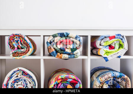 color blankets in style a patchwork put in a roll lie in different cells of a box on a white background and the place for the text over them from above. Stock Photo