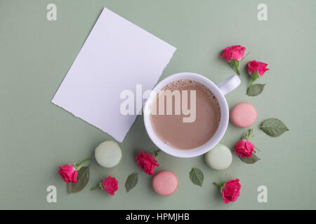 Macaroons, coffee and rose on green background. Top view. Flat lay Stock Photo