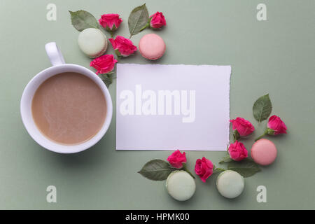 Macaroons, coffee and rose on green background. Top view. Flat lay Stock Photo
