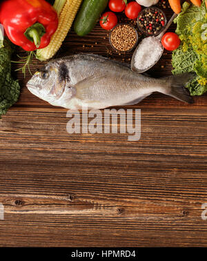 Fresh raw fish with vegetables on old wooden background with space for text Stock Photo