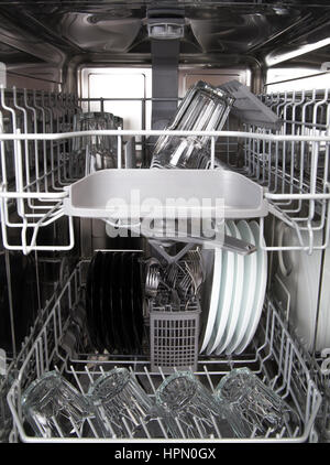 Clean glasses and white plates in modern dishwasher machine Stock Photo