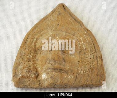 Roman antefix. Vertical block which terminates the covering tiles of the roof. High-imperial era. Roman antefix. High-imperial era. Male head, covered by a cucullus. National Archaeological Museum. Tarragona. Catalonia, Spain. Stock Photo