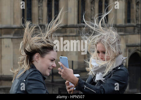 Women attempt to take a 'selfie' on Westminster Bridge, London, as flights have been cancelled and commuters were warned they faced delays after Storm Doris reached nearly 90mph on its way to batter Britain. Stock Photo