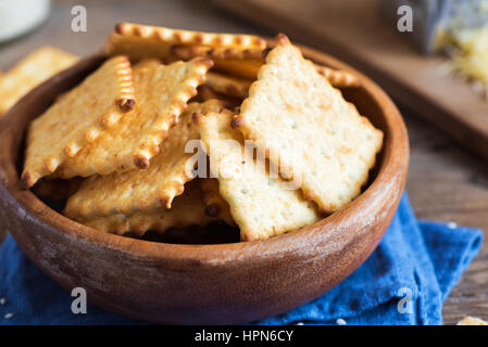 Homemade thin crispy cheesy crackers with sesame seeds in rustic wooden bowl - fresh organic homemade baking cheese crackers snack Stock Photo