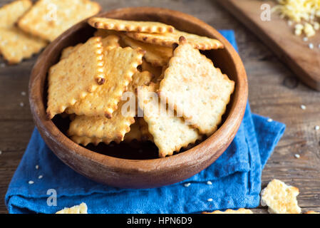 Homemade thin crispy cheesy crackers with sesame seeds in rustic wooden bowl - fresh organic homemade baking cheese crackers snack Stock Photo