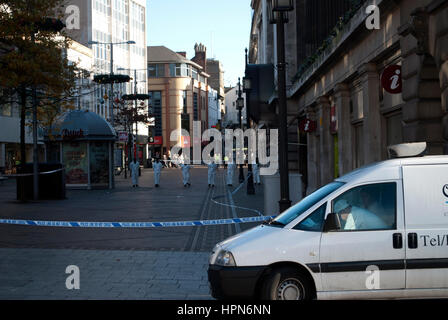 Police conduct a forensic search behind cordon on Long Row, Nottingham after a stabbing incident Stock Photo