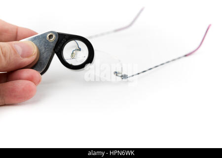 Male Hand Holding Magnifying Glass Examing Glasses Isolated on a White Background. Studio Shot Stock Photo