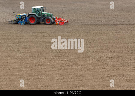 Farmer seeding crops at field in spring Stock Photo