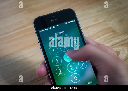 Bangkok, Thailand - February 22, 2017 : Apple iPhone5s held in one hand showing its screen with numpad for entering the passcode. Stock Photo
