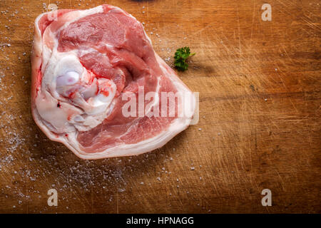 One piece of raw pork with salt and parsley on wood with copy space Stock Photo