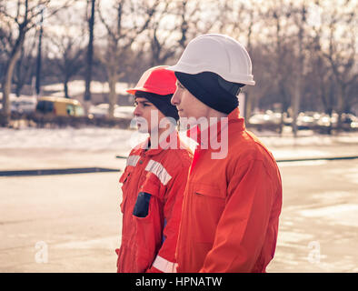 team of  young engineers tired after heavy working day. They wear safety helmets. Stock Photo