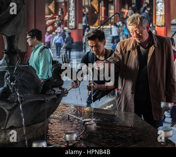 Tokyo, Japan - November 6, 2015. Fountain with dragon's statues. People cleaning hands and drinking water in purification before entering Sensoji Temp Stock Photo