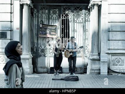 Street jazz musicians (woman and man) play a saxophone and guitar in front of a historical old building on Istiklal avenue in Beyoglu Istanbul. Arabic Stock Photo