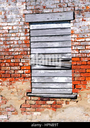 Background image shows an old brick building smeared with mortar.  Lone window is boarded up with white washed and weathered boards. Stock Photo