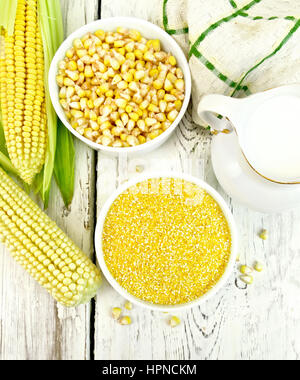 Corn grits and corn in two bowls, a napkin and cobs on the background of the wooden planks on top Stock Photo