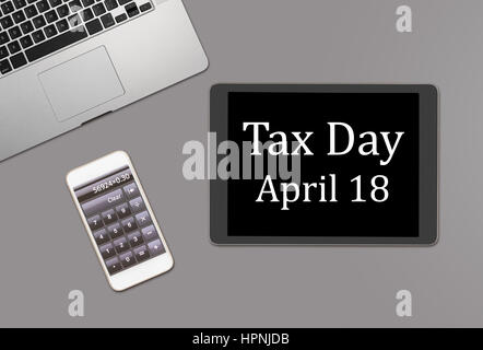 Overhead clean desk for laptop, smartphone and tablet computer with message for tax day 2017 as April 18 Stock Photo